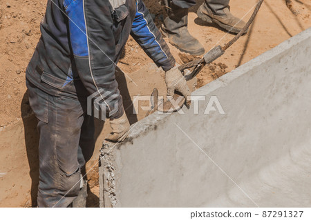 The hand of construction worker male take a heavy iron hook lifting mechanism with a steel cable rope to a concrete, cement structure on construction site industry The hand of construction worker male take a heavy iron hook lifting mechanism with a steel cable rope to a concrete, cement structure on construction site industry 87291327