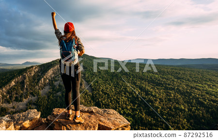 A traveler with a backpack in the mountains at sunset. A traveler with a backpack on the background of mountains, rear view. Hiking trips. A tourist girl on the background of a mountain landscape A traveler with a backpack in the mountains at sunset. A traveler with a backpack on the background of mountains, rear view. Hiking trips. A tourist girl on the background of a mountain landscape 87292516