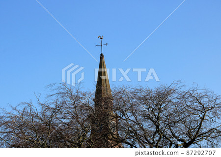 Village Church Steeple Behind Winter Trees on a Blue Sky 87292707