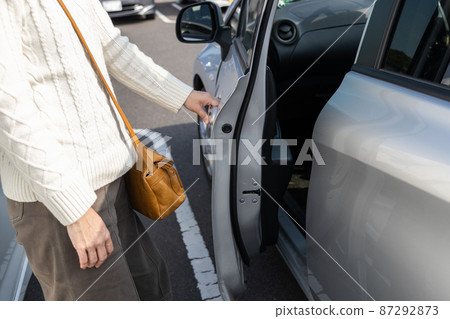 Woman getting out of the car in a small parking lot Woman getting out of the car in a small parking lot 87292873