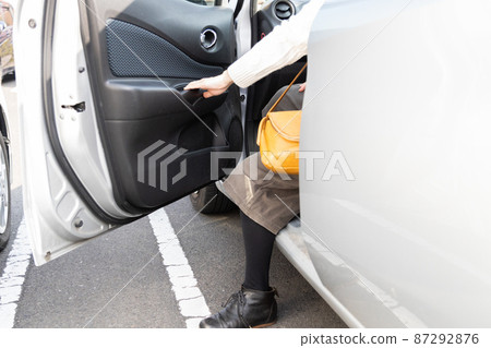 Woman getting out of the car in a small parking lot Woman getting out of the car in a small parking lot 87292876