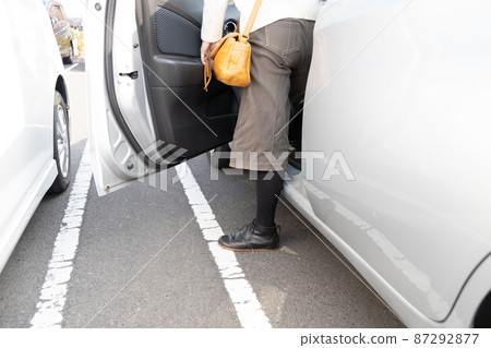 Woman getting out of the car in a small parking lot 87292877