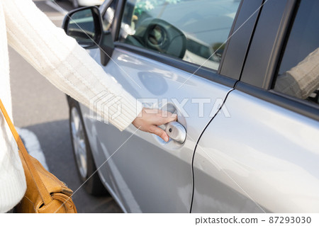 A woman trying to open the passenger seat of a car 87293030