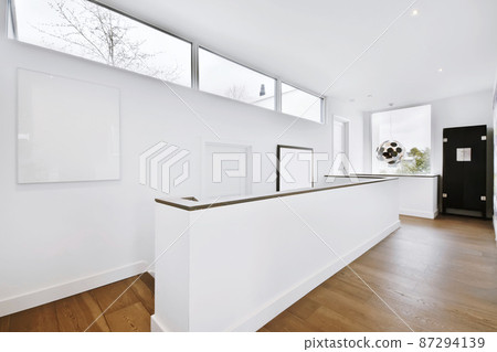 A long corridor in a minimalist style with windows and wooden floors A long corridor in a minimalist style with windows and wooden floors 87294139