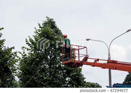 man with a chainsaw, standing on a platform man with a chainsaw, standing on a platform 87294677