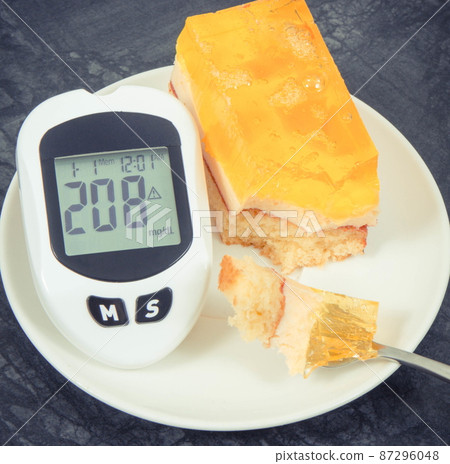 Glucometer with high sugar level and creamy fruit cake with jelly. Nutrition during diabetes 87296048