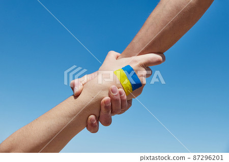 Lend a hand help painted in ukrainian flag colors against blue sky. Stand with Ukraine 87296201