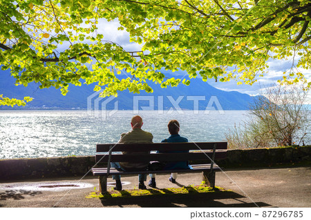 A couple relaxing on a bench by Lake Geneva (Montreux, Switzerland) 87296785