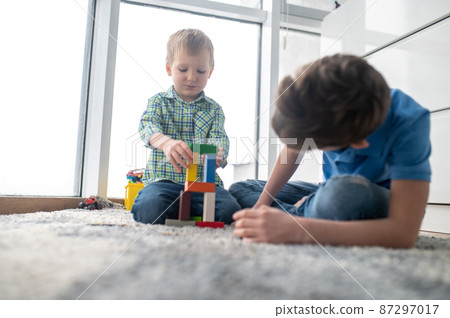Two boys playing with toy blocks in a room Two boys playing with toy blocks in a room 87297017