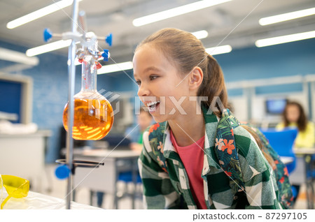 Girl with delight looking at flask in chemistry class 87297105