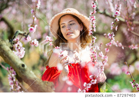 Young girl standing in spring blooming garden Young girl standing in spring blooming garden 87297403