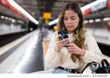 Young attractive girl in jeans waiting for subway train on a platform 87297634