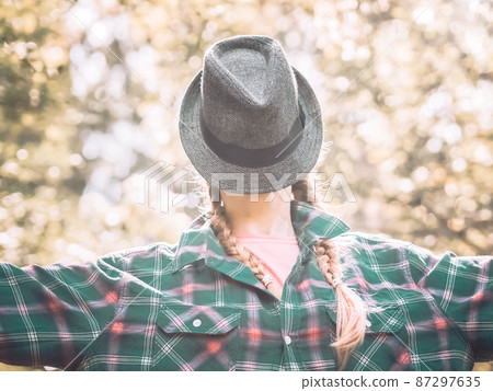Portrait of a lady with a hat put on her face in a plaid shirt standing outdoors. Posterization 87297635