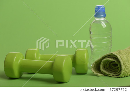 Dumbbells in bright green color, water bottle and cloth Dumbbells in bright green color, water bottle and cloth 87297732