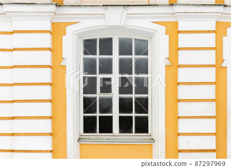 Classical window with white frame in yellow stone wall Classical window with white frame in yellow stone wall 87297969