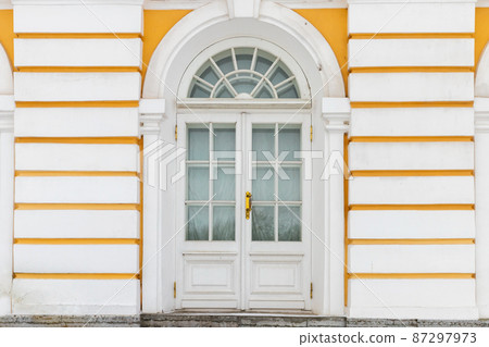 Old white wooden door in yellow wall, background texture 87297973