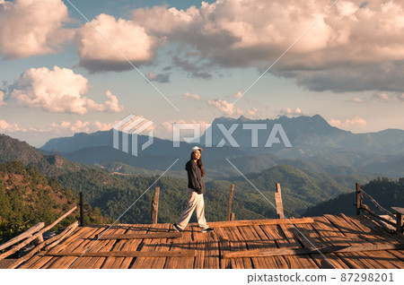 Happy asian woman standing on balcony and Doi Luang Chiang Dao mountain from Hadubi viewpoint in the sunset Happy asian woman standing on balcony and Doi Luang Chiang Dao mountain from Hadubi viewpoint in the sunset 87298201