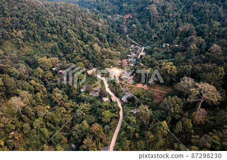 Aerial view of local rural village with gravel road through in the valley on faraway at countryside among the tropical rainforest 87298230