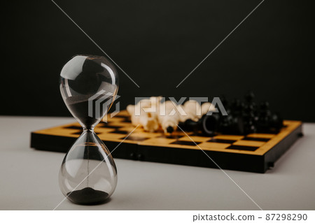 Hourglass and chessboard on a grey background. Strategy, management or leadership concept 87298290