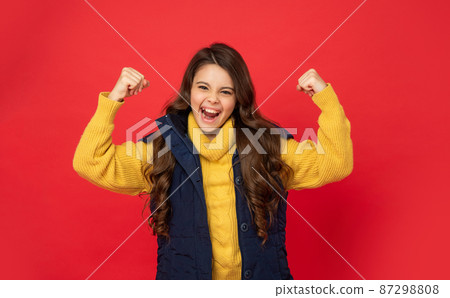 happy successful kid with curly hair in sweater. female fashion model. teen girl in down vest. 87298808