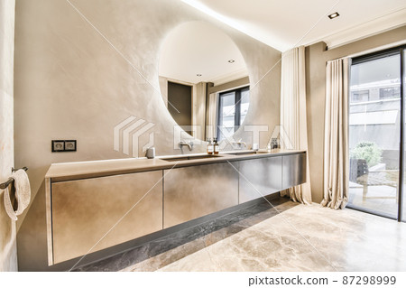 Attractive bathroom with a large round mirror and two sinks 87298999