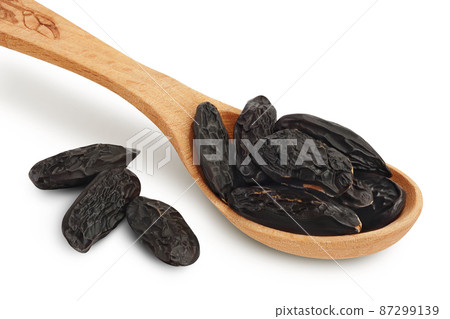 Tonka bean in wooden spoon isolated on white background with clipping path and full depth of field. Bean of Dipteryx odorata 87299139
