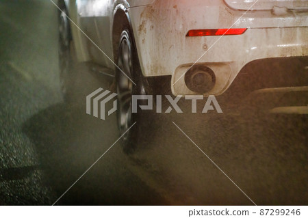 dirty water ejecting out from white car driving on night winter road 87299246