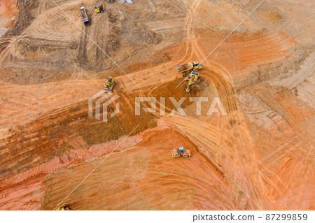 Industrial excavator loading soil material from highway construction site into a dumper truck Industrial excavator loading soil material from highway construction site into a dumper truck 87299859