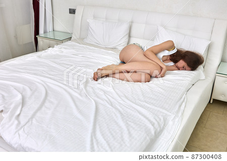 High body temperature of woman who lies on bed inside. 87300408