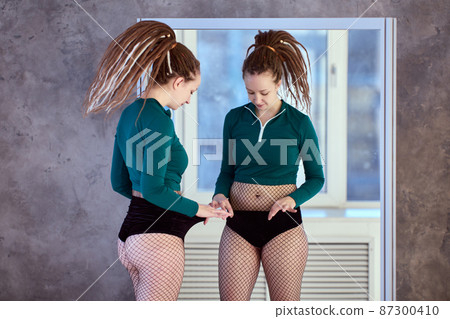 Burning calories in training, dancer explores state of subcutaneous fat on her waist. 87300410