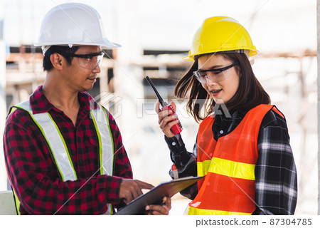 Two Asian engineer foreman architect worker man and woman talking at building construction site Two Asian engineer foreman architect worker man and woman talking at building construction site 87304785
