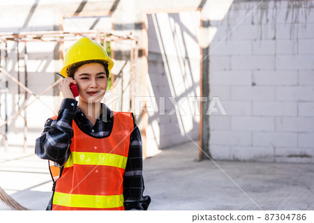Asian engineer foreman architect worker woman working at building construction site talking with radio 87304786