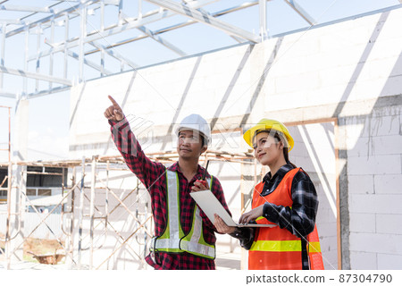 Asian engineer foreman worker man and woman working at building construction site use laptop and talking with radio 87304790