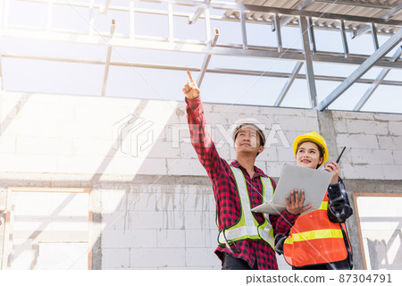 Asian engineer foreman worker man and woman working at building construction site use laptop and talking with radio 87304791