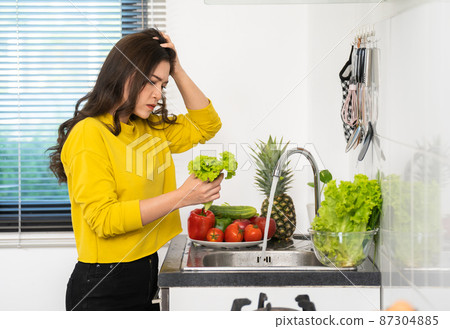 stressed woman washing vegetables in the sink in the kitchen at home 87304885