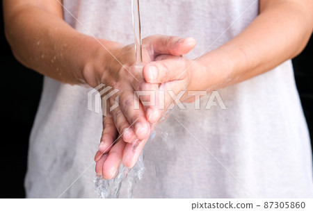 Hands of woman wash their hands in a sink with foam to wash the skin and water flows through the hands. Concept of health, cleaning and preventing germs and coronavirus from contacting hands 87305860