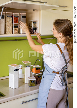Laughing young female housewife posing during general cleaning, tidying up in cupboard kitchen 87305940