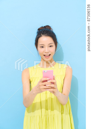 有智能手機淺藍色背景的婦女 有智能手機淺藍色背景的婦女 87306536