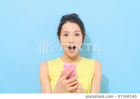 有智能手機淺藍色背景的婦女 87306540