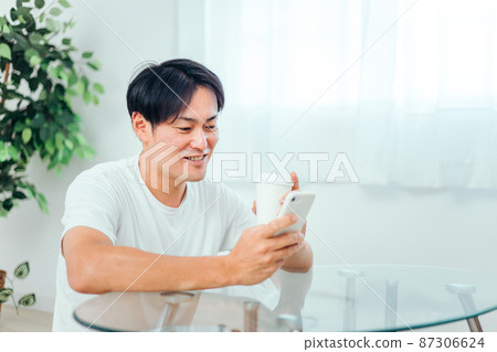 一個男人在房間裡看智能手機(微笑) 一個男人在房間裡看智能手機(微笑) 87306624