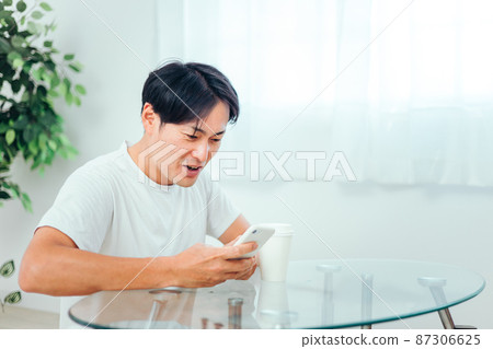 一個男人在房間裡看智能手機(笑) 一個男人在房間裡看智能手機(笑) 87306625