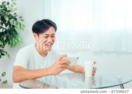 一個男人在房間裡看智能手機(笑) 一個男人在房間裡看智能手機(笑) 87306627