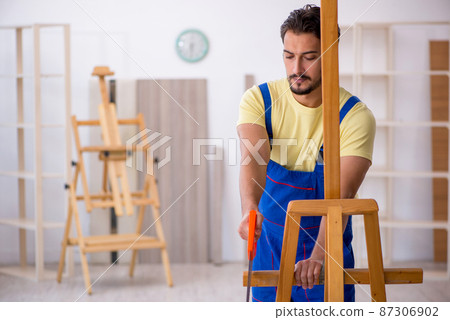 Young repairman repairing easel at home Young repairman repairing easel at home 87306902