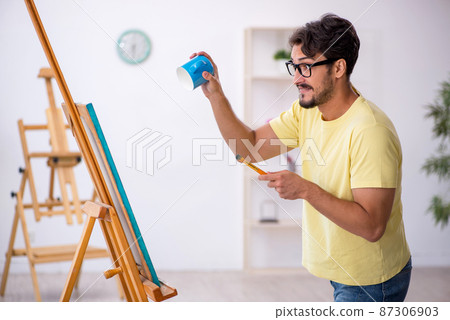 Young man enjoying painting at home 87306903
