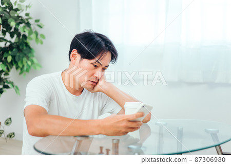 一個男人在房間裡看智能手機(不適) 一個男人在房間裡看智能手機(不適) 87306980