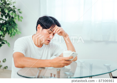 A man looking at a smartphone in the room (unwell) 87306981