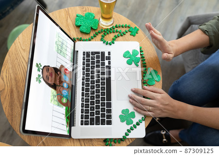 Caucasian woman at bar making st patrick's day video call waving to female friend on laptop Caucasian woman at bar making st patrick's day video call waving to female friend on laptop 87309125