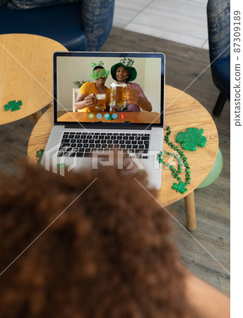 Man at bar making st patrick's day video call with two smiling mixed race male friends on laptop Man at bar making st patrick's day video call with two smiling mixed race male friends on laptop 87309189