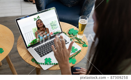 Caucasian woman at bar making st patrick's day video call waving to friend blowing kiss on laptop Caucasian woman at bar making st patrick's day video call waving to friend blowing kiss on laptop 87309258