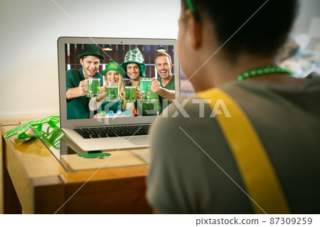 Mixed race woman having st patrick's day video call with friends raising glasses on laptop at home Mixed race woman having st patrick's day video call with friends raising glasses on laptop at home 87309259